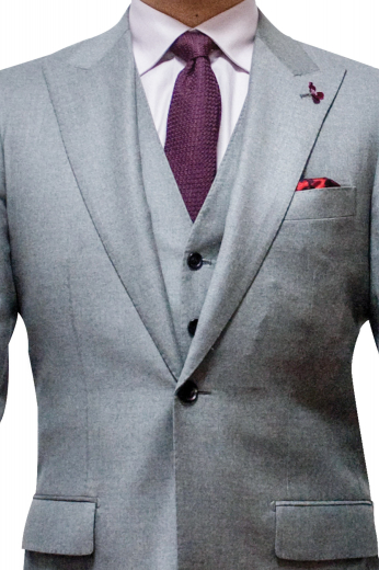 Mens made to order light grey 3pc suit in cashmere wool. Features a bespoke slim fit vest with 6 front buttons, a handmade jacket with 2 peak lapels and 1 front close buttons, and tailor made slim fit dress pants with sewn down pleats. The mens handmade slim fit jacket has 1 boutonniere on the left lapel, 1 upper welt pocket, 2 lower flapped pockets, and hand moulded shoulders. The mens bespoke vest has 2 welted lower pockets. Mens handmade dress pants have 2 front slash pockets, a 2 point button and hook closure, and a zip fly.
