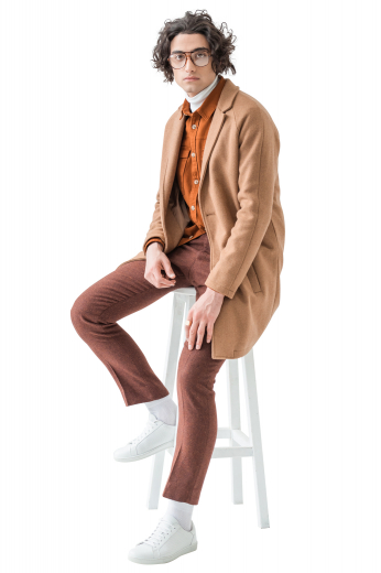 This men's custom made tan colored coat is tailor made in a fine wool and tweed, featuring a single breasted button closure, slanted welt pockets, and a center vent. 